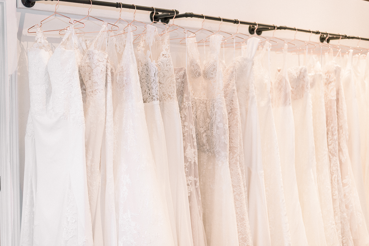 A row of white wedding dresses on hangers in a bridal store.