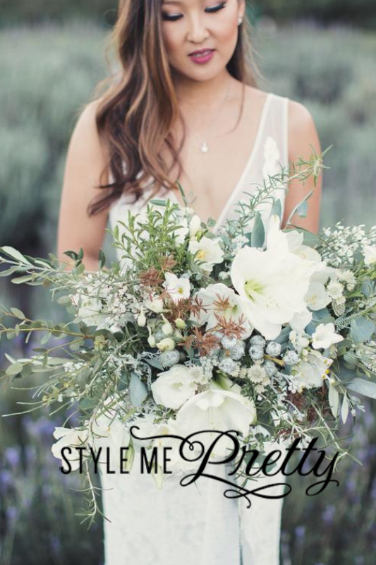 A woman in a white dress holds a large and elaborate bouquet of white flowers and greenery. The image features text that reads "Style Me Pretty," showcasing the elegance curated by Tahoe wedding planners.