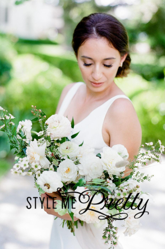 A woman in a white dress holds a large bouquet of white flowers and greenery. The text "Style Me Pretty" is overlaid on the lower part of the image.