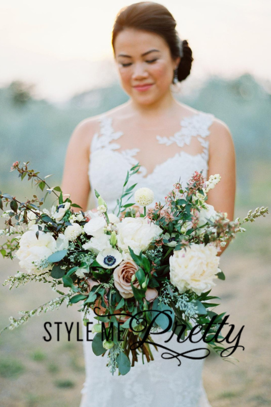 A bride in a white lace dress holds a large bouquet of white and green flowers. The text "Style Me Pretty" is displayed across the lower part of the image, a testament to the magic created by Tahoe wedding planners.