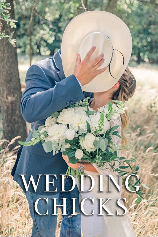 A couple kisses behind a cowboy hat, holding a bouquet of white flowers, with trees and grass in the background. Text at the bottom reads "Wedding Chicks.