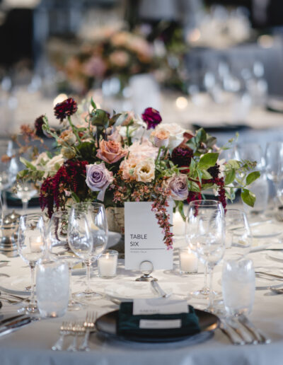 Elegant table setting with floral centerpiece, labeled "Table Six," surrounded by glassware, candles, and place settings.