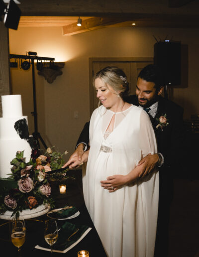 Bride and groom cutting a wedding cake together, surrounded by flowers and candles.