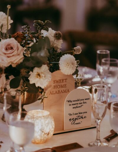 Table with floral centerpiece, engraved wooden signs with quotes, candles, and glassware.