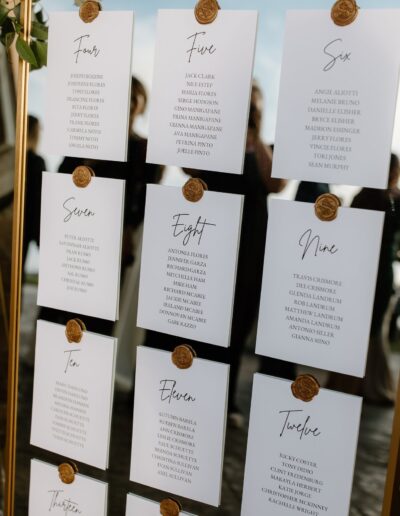 Wedding seating chart on a mirror with wax seals, surrounded by candles and greenery.