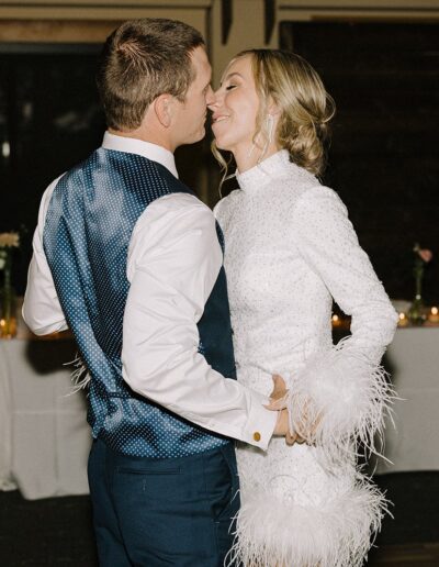 A couple dressed in formal attire dances closely in a dimly lit room, with a "Drunk in Love" neon sign and a decorated table in the background.