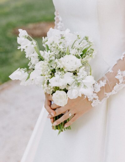 A bride in a white gown holds a bouquet of white flowers.