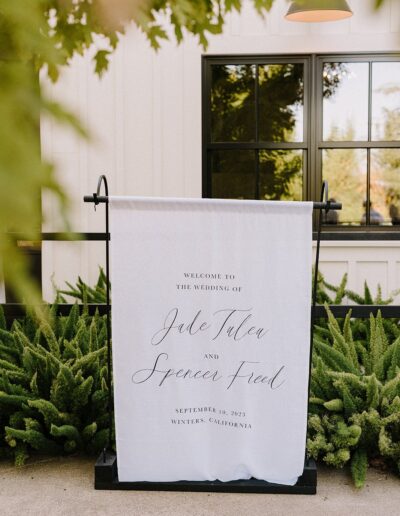 Wedding welcome sign for Jade Tulea and Spencer Freed on September 10, 2023, in Winters, California, displayed outdoors with greenery.