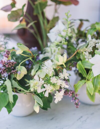 A floral arrangement featuring white and purple flowers with green leaves on a light marble surface.