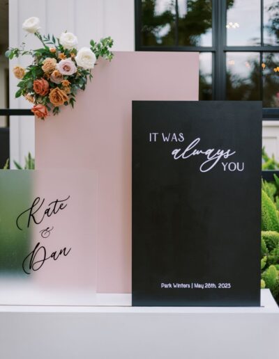 Wedding signage with floral arrangement. Text reads: "Kate & Dan" and "It was always you," dated "Park Winters | May 26th, 2023.