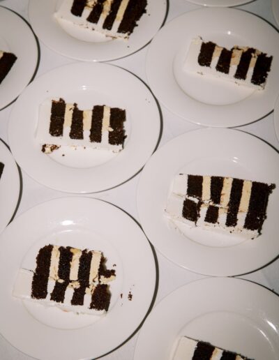 Several slices of chocolate and vanilla layered cake are arranged on white plates on a table.