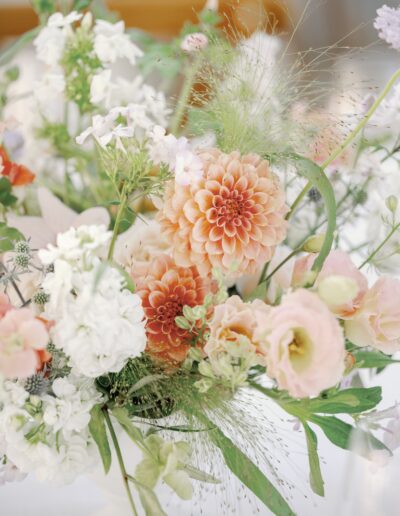 A bouquet featuring peach dahlias, white stock flowers, and green foliage.