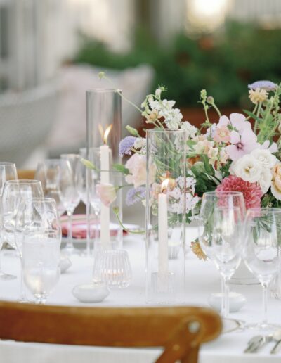 Elegant dining table setup with floral centerpiece, glassware, candles, and neatly arranged place settings.