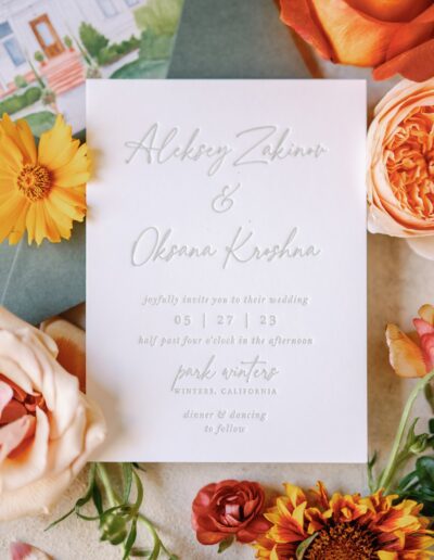 Wedding invitation with flowers. Text includes names Alexey Zakinov and Oksana Krishna, date 05.27.23, and venue Park Winters, California. Dinner and dancing mentioned.