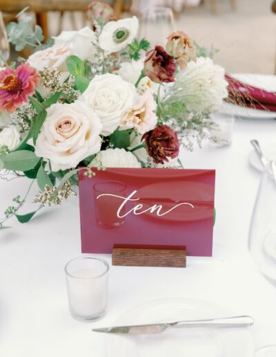 A table centerpiece featuring a floral arrangement with roses and a red card displaying the word "ten" in cursive.