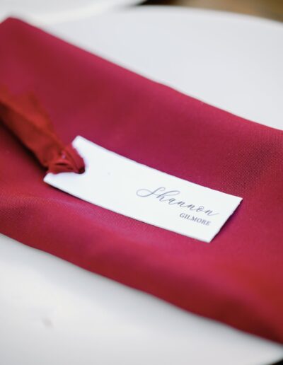 A red napkin with a place card reading "Shannon Gilmore" is set on a white plate.