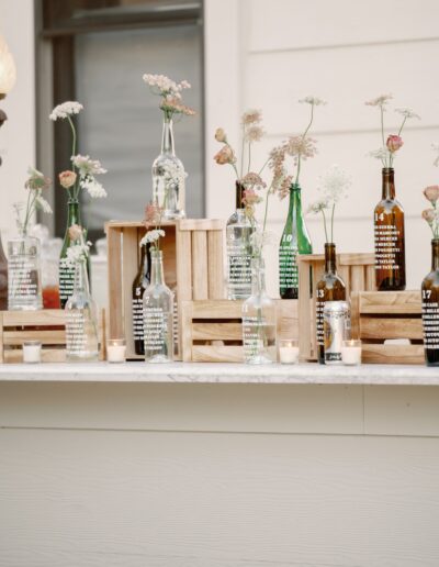 Wooden crates with glass bottles and delicate flowers are arranged on a white countertop, creating a simple decorative display.