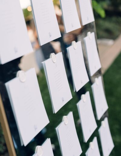 A display board with multiple rows of clipped white cards, each embossed with a seal at the top, set outdoors.