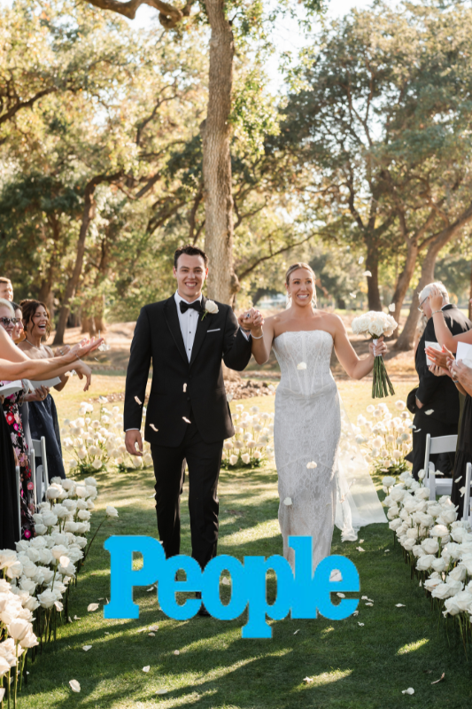 A bride and groom walk down the aisle outdoors, surrounded by guests throwing petals. The word "People" is displayed in large blue letters in the foreground.