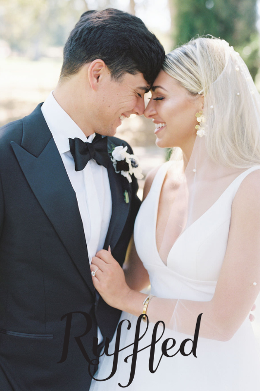 A bride and groom in formal attire stand close, smiling at each other outdoors. The word "Ruffled" is at the bottom.