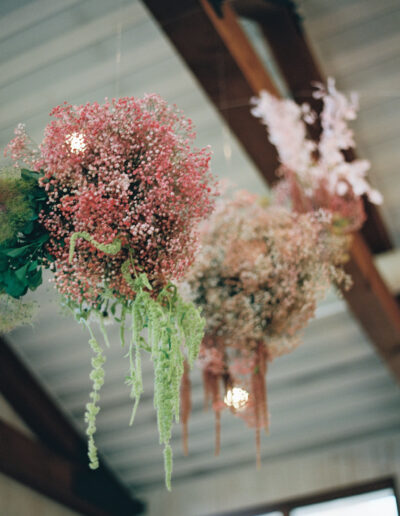 Hanging floral arrangements with pink and green flowers suspended from a wooden ceiling.