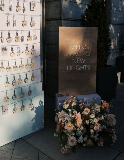 Display with seating tags and a sign that reads "Taking Love to New Heights," accompanied by a floral arrangement.