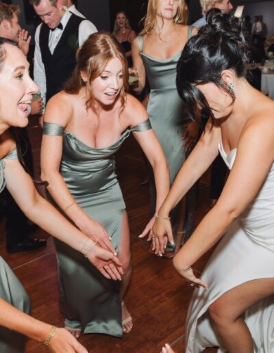 People in formal attire dancing energetically at an indoor event.