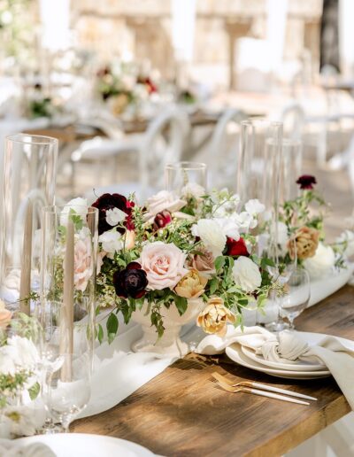 Elegant table setting with floral arrangements, tall candles, and neatly folded napkins on a wooden table.