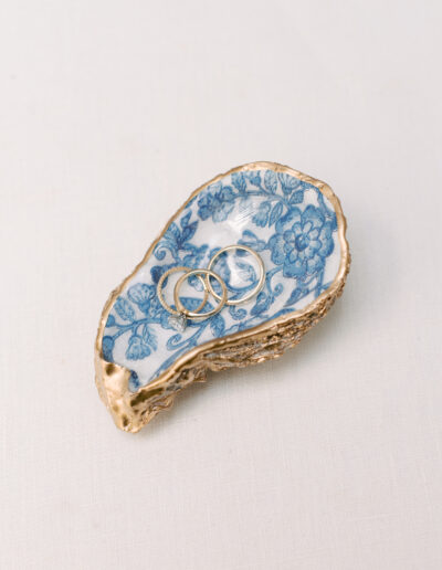 Two rings rest on a decorative blue and white floral dish with a gold rim, set against a light background.