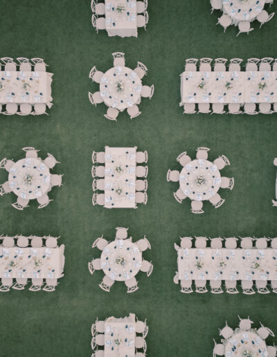 Aerial view of a Solage Calistoga wedding setup with rectangular and round tables arranged on grass, each table set with chairs, plates, and glassware.