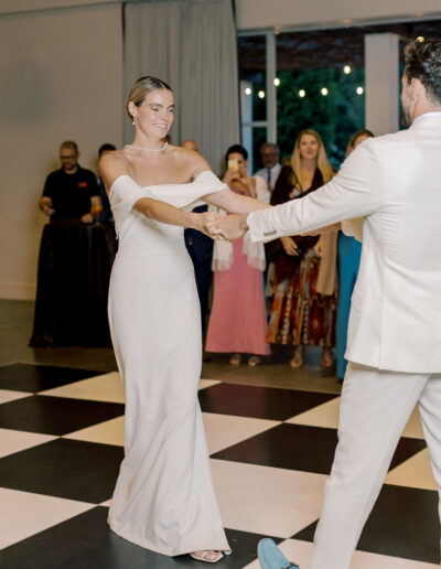 A bride and groom dance together on a black-and-white checkered floor at their Solage Calistoga wedding, with guests watching in the background.